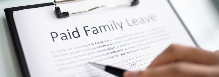 Person with pen in hand filling out Paid Family Leave paperwork for FMLA