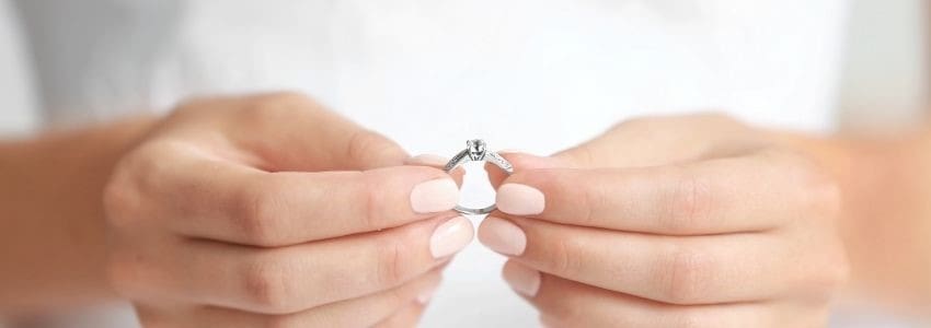 A woman's hands holding a diamond engagement ring signaling an upcoming name change.