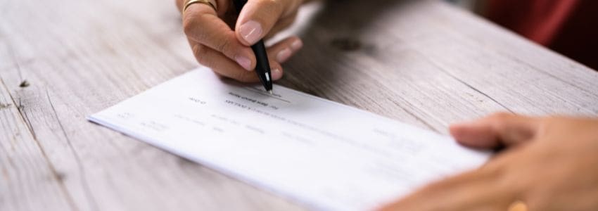 Close up of a person signing a live check.