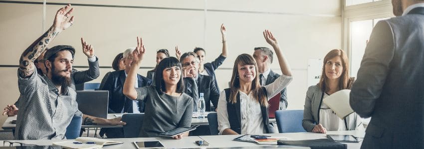 A classroom of professionals raising their hands