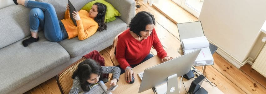 Woman working from home while her daughters do homework
