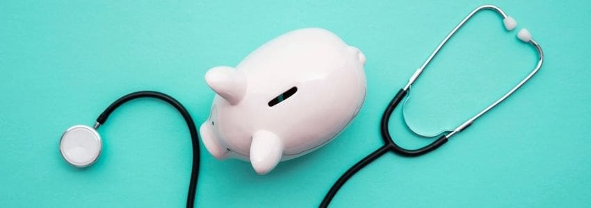 Stethoscope laying next to a piggy bank representing saving money for an FSA or HSA.