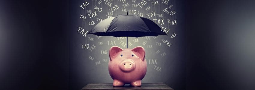 Piggy bank with an umbrella over it protecting it from taxes that are falling all around it.