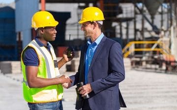 Two men wearing hard hats working at a construction site, representing Health, Safety & Security - part of our Outsourced HR Solutions