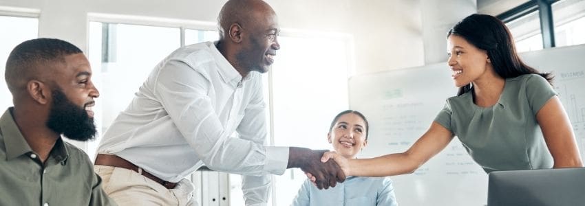 A new hire shaking hands with her colleagues she's meeting in her 90-day introductory period.