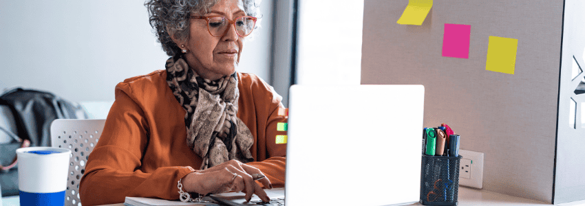 A mature woman sitting at her desk working on her computer.