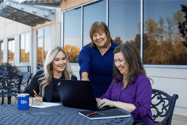 Three team members sitting at a table discussing the key takeaways of their Five Behaviors training.