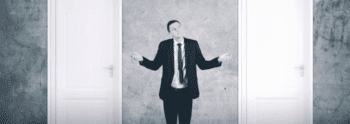 Man standing between two doors trying to make a decision
